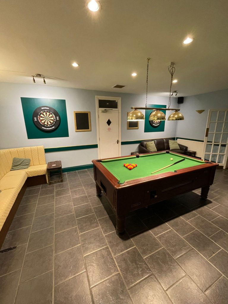 pool room with pool table, two dart boards and two sofas